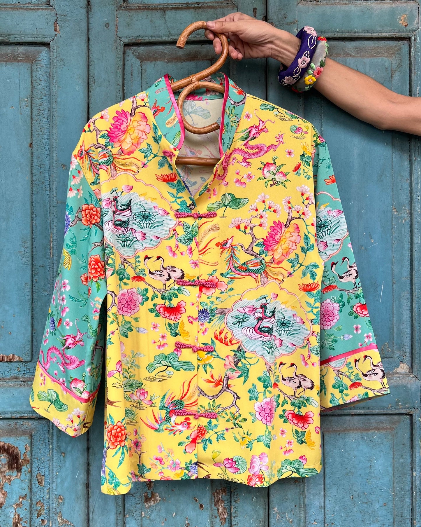 Colorful floral-patterned shirt on a hanger against a rustic blue wooden door.