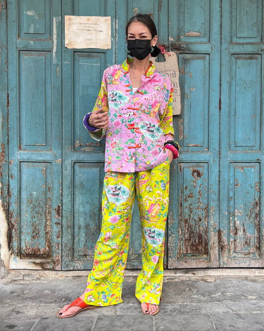 Woman wearing a colorful floral outfit standing in front of a weathered blue door.