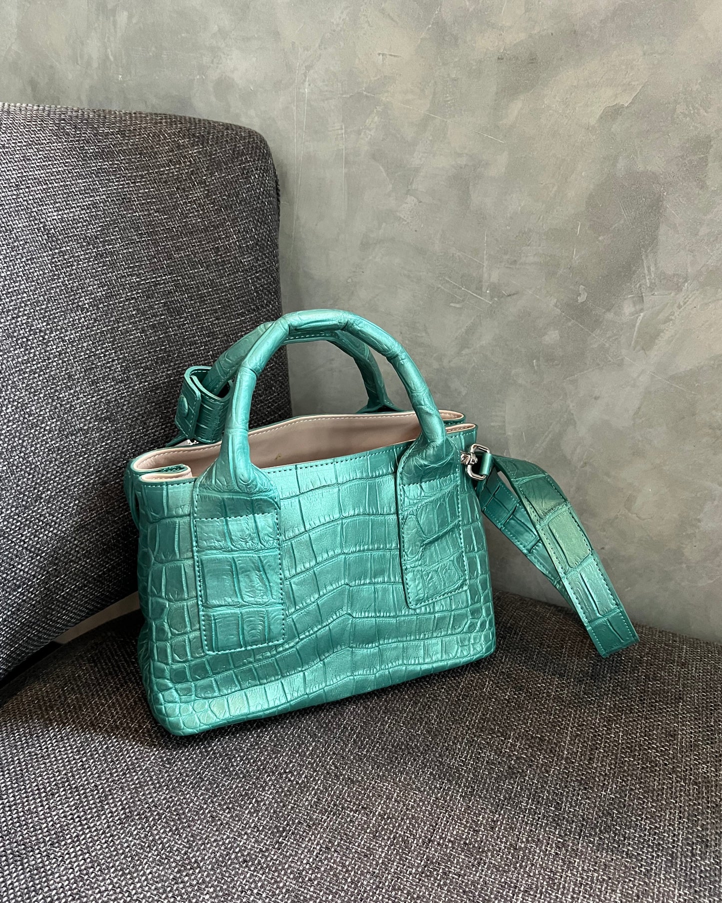 Green crocodile-patterned handbag on a gray surface