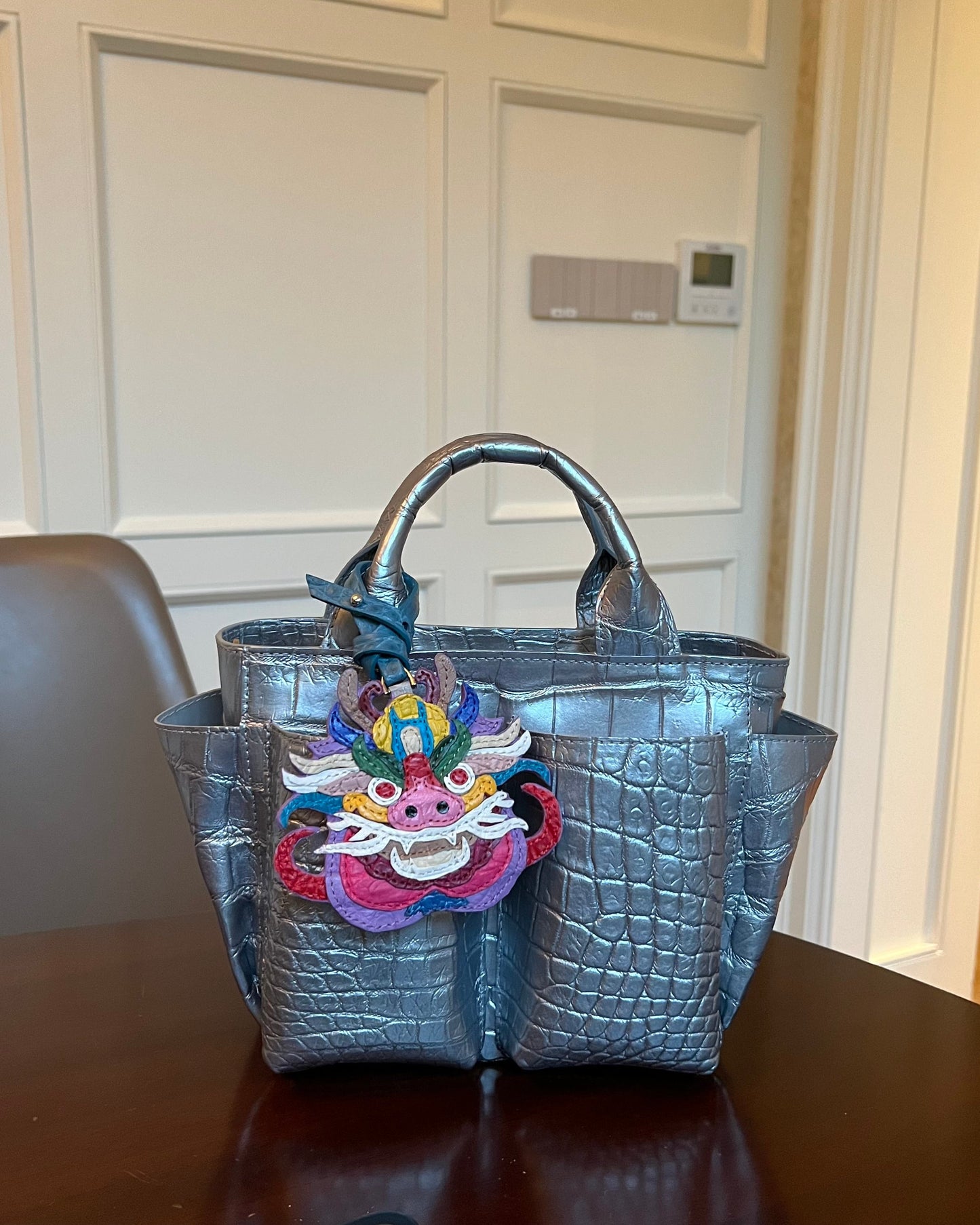 Silver handbag with colorful dragon design on a table