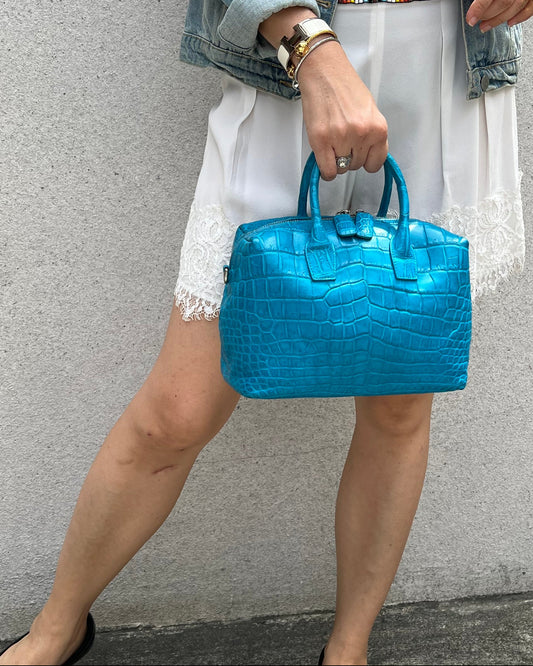 Person holding a blue handbag on a sidewalk