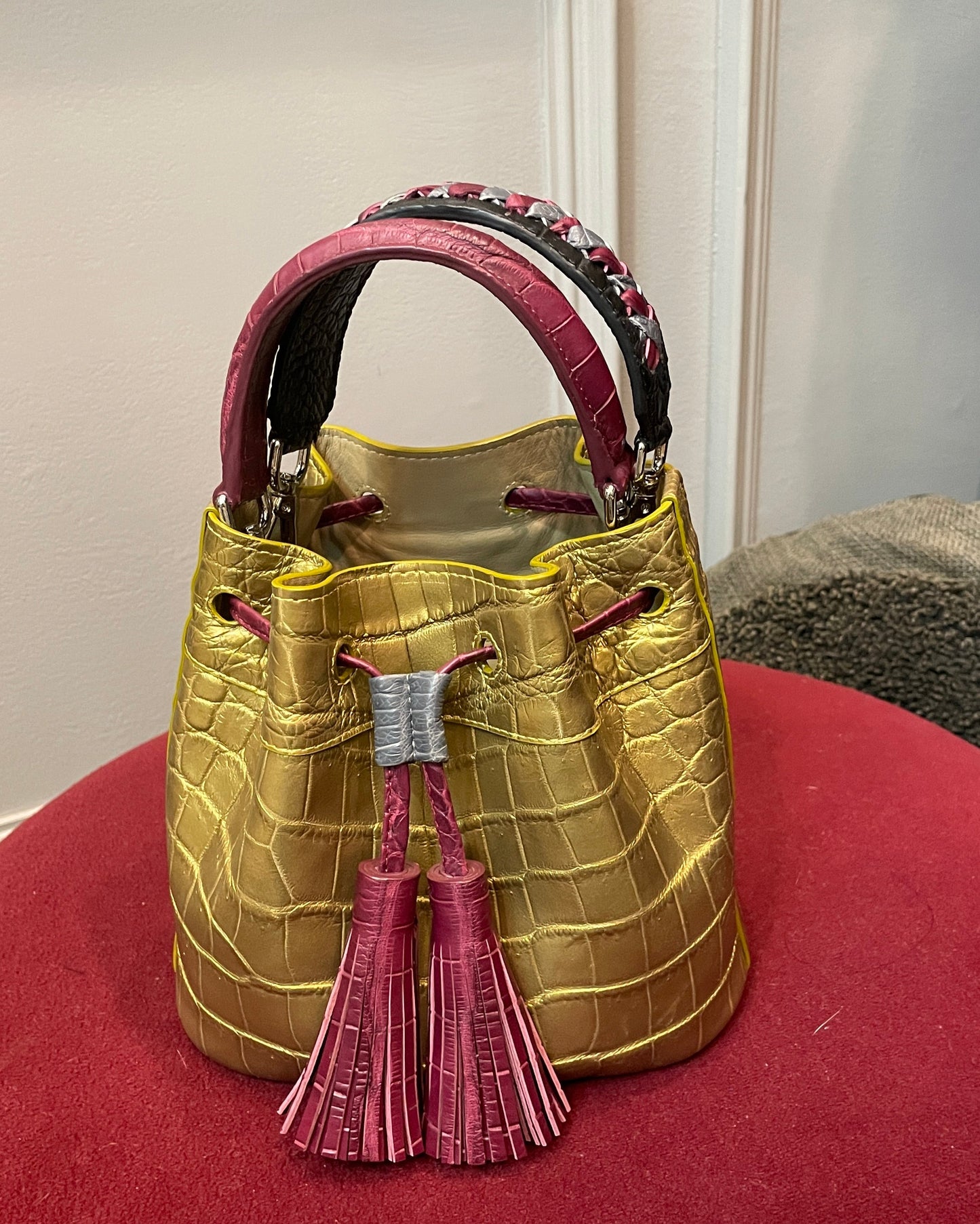 Gold handbag with pink accents on a red surface