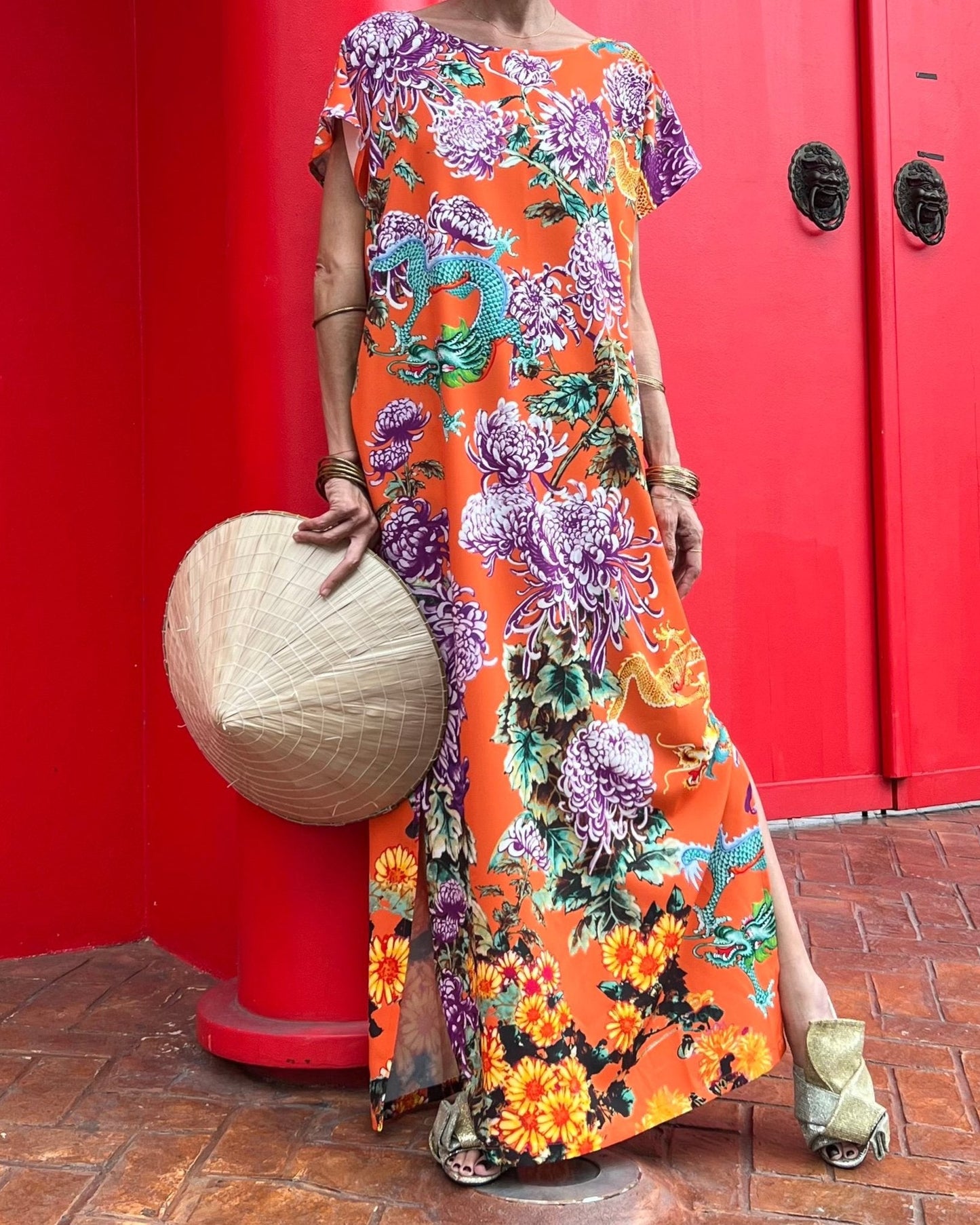 Person wearing a colorful floral dress against a red wall.
