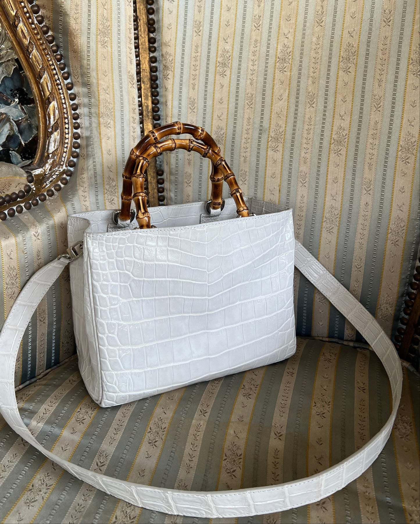 White handbag with gold handle on a textured surface
