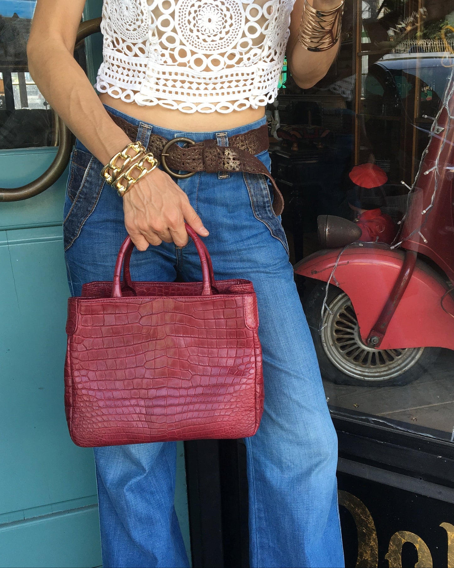 Person holding a red handbag in front of a store entrance