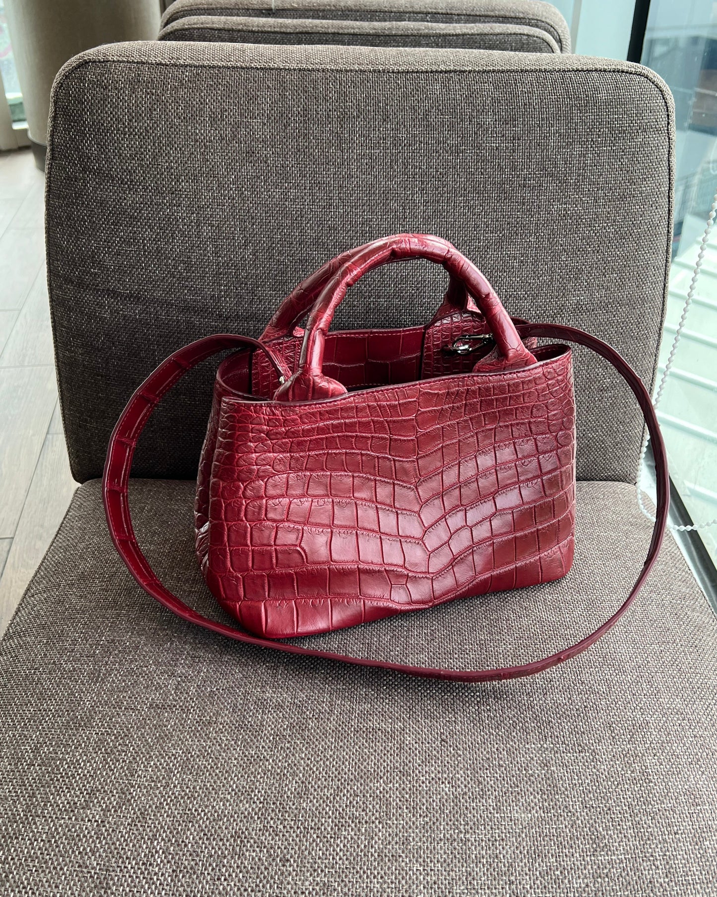 Red handbag with a crocodile pattern on a gray chair