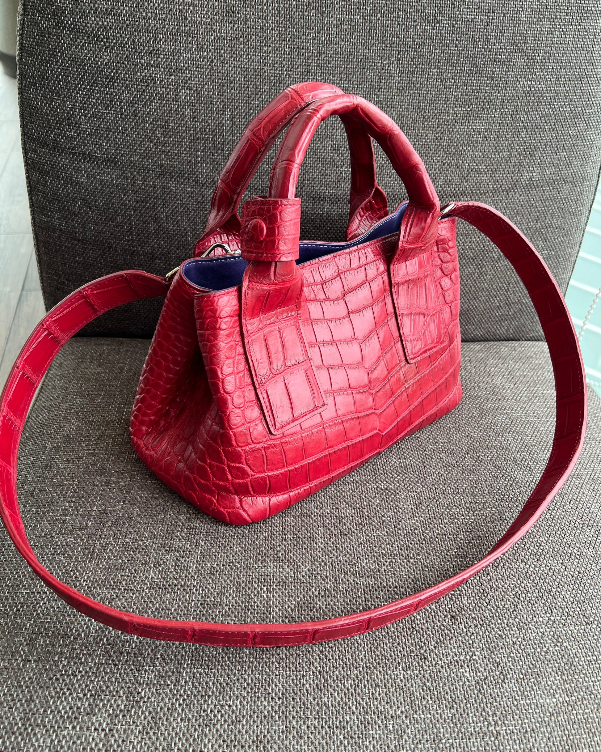 Red handbag with a textured pattern on a gray surface