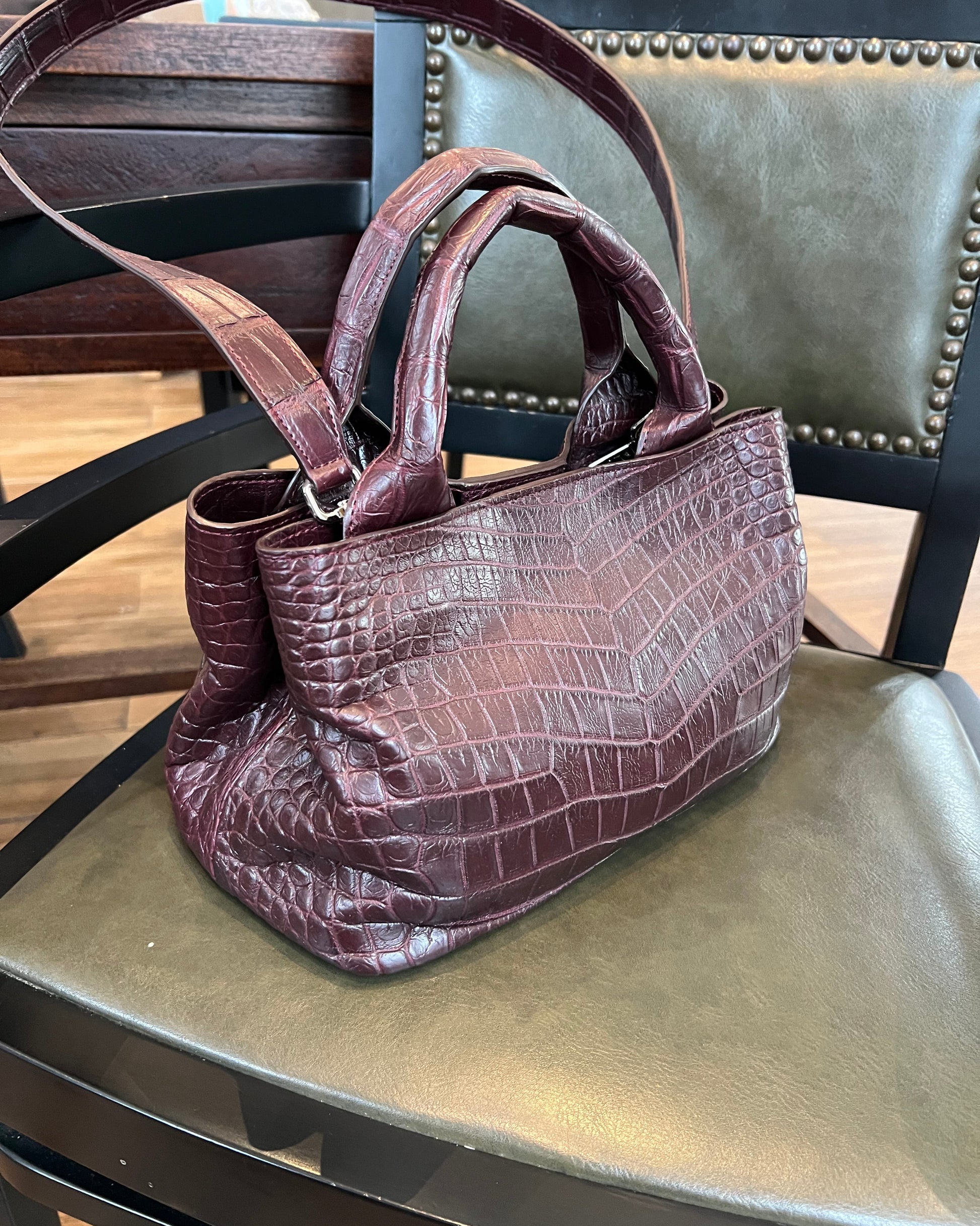 Brown leather handbag on a chair with a wooden floor background