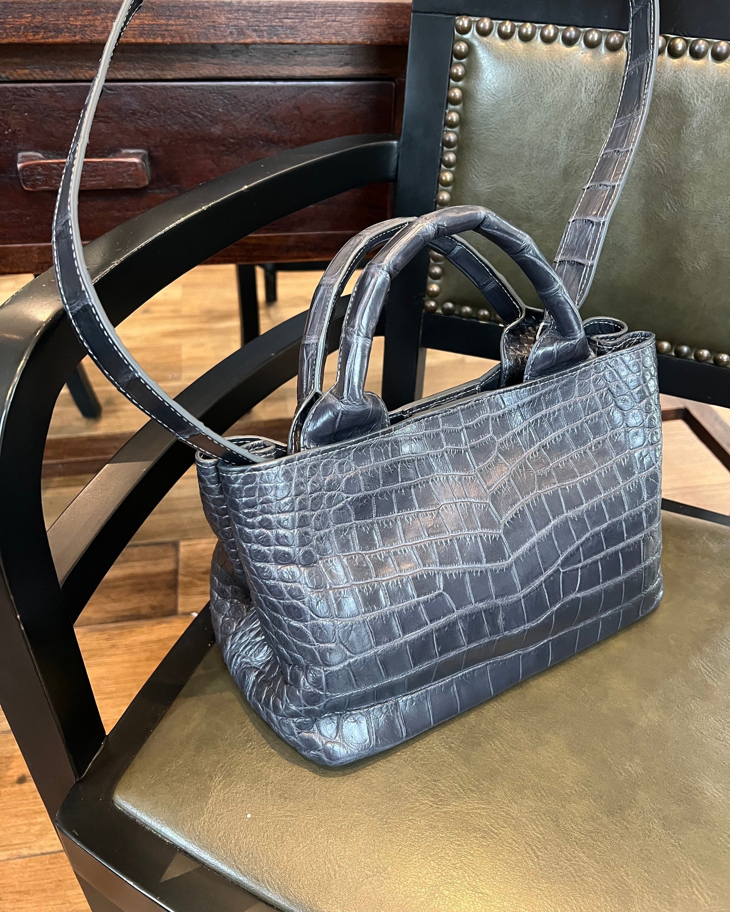 Gray crocodile-patterned handbag on a chair
