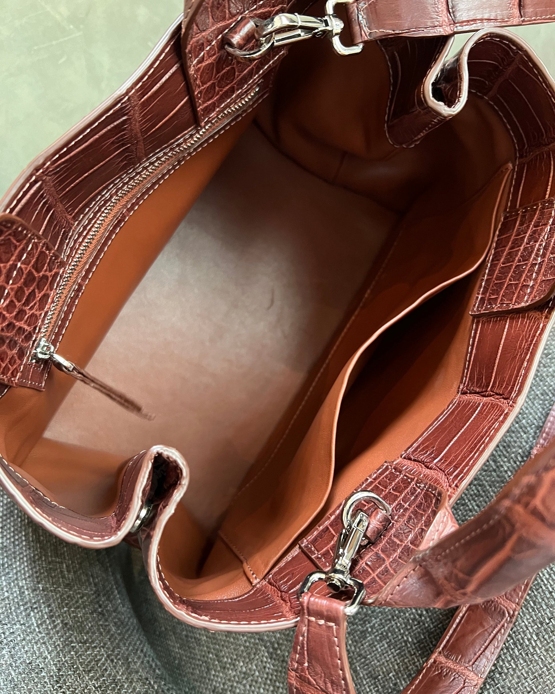 Brown leather handbag with silver hardware on a textured surface