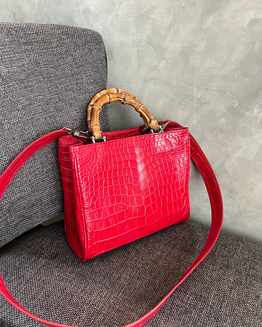 Red handbag with a bamboo handle on a textured surface