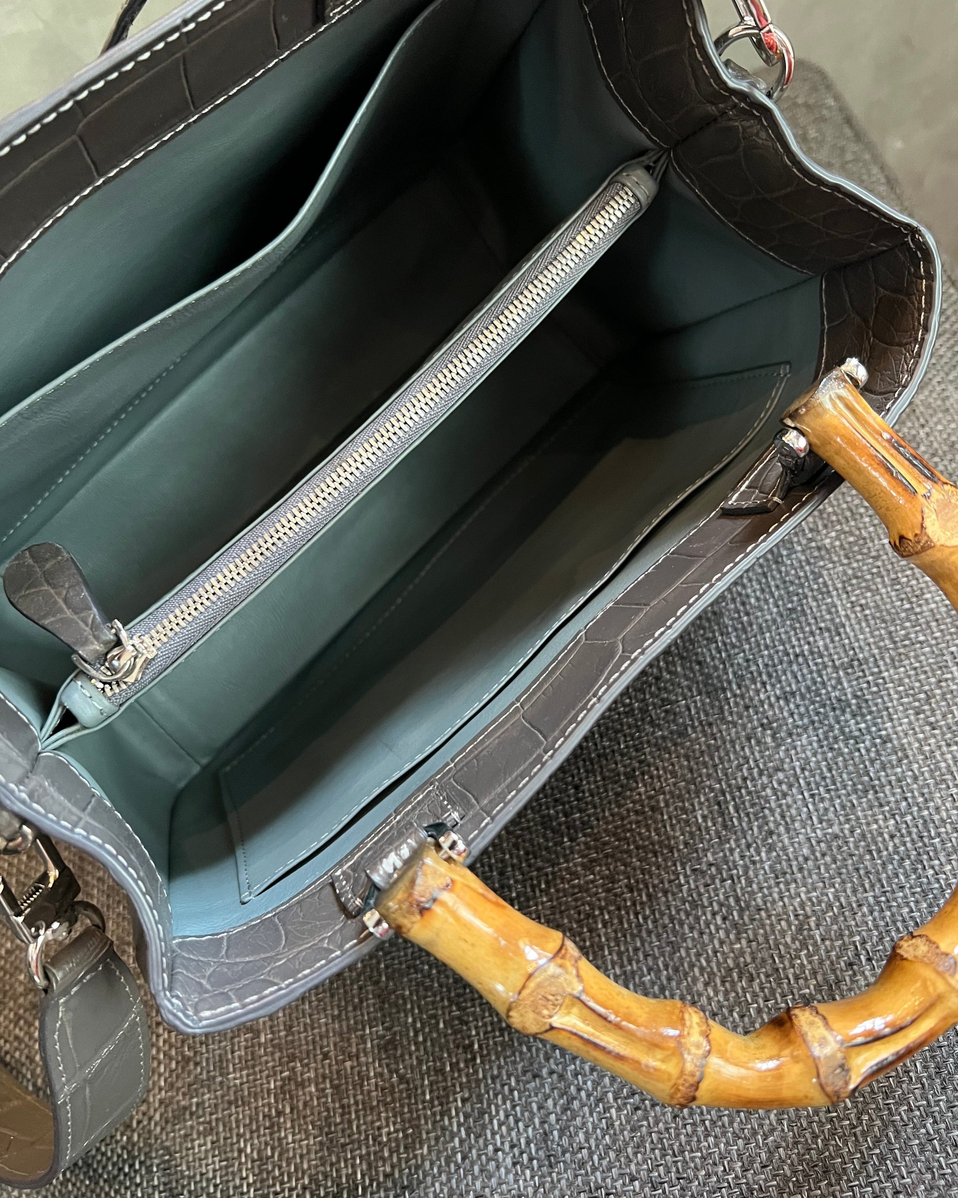 Open handbag with bamboo handle on a textured surface