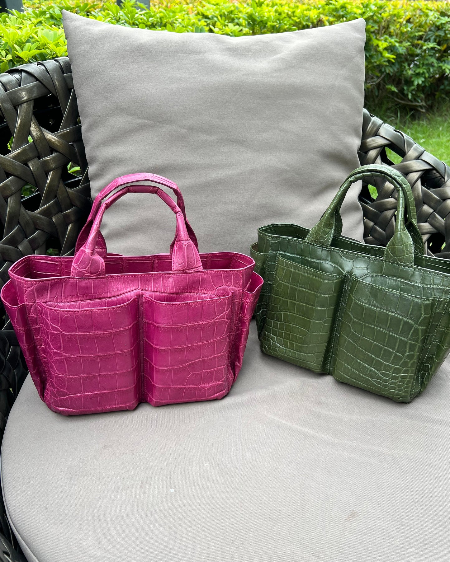 Two handbags, one green and one pink, on a cushioned chair outdoors.