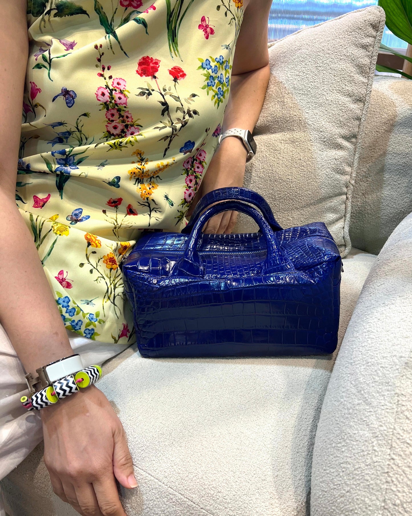 Person holding a blue handbag on a light-colored couch