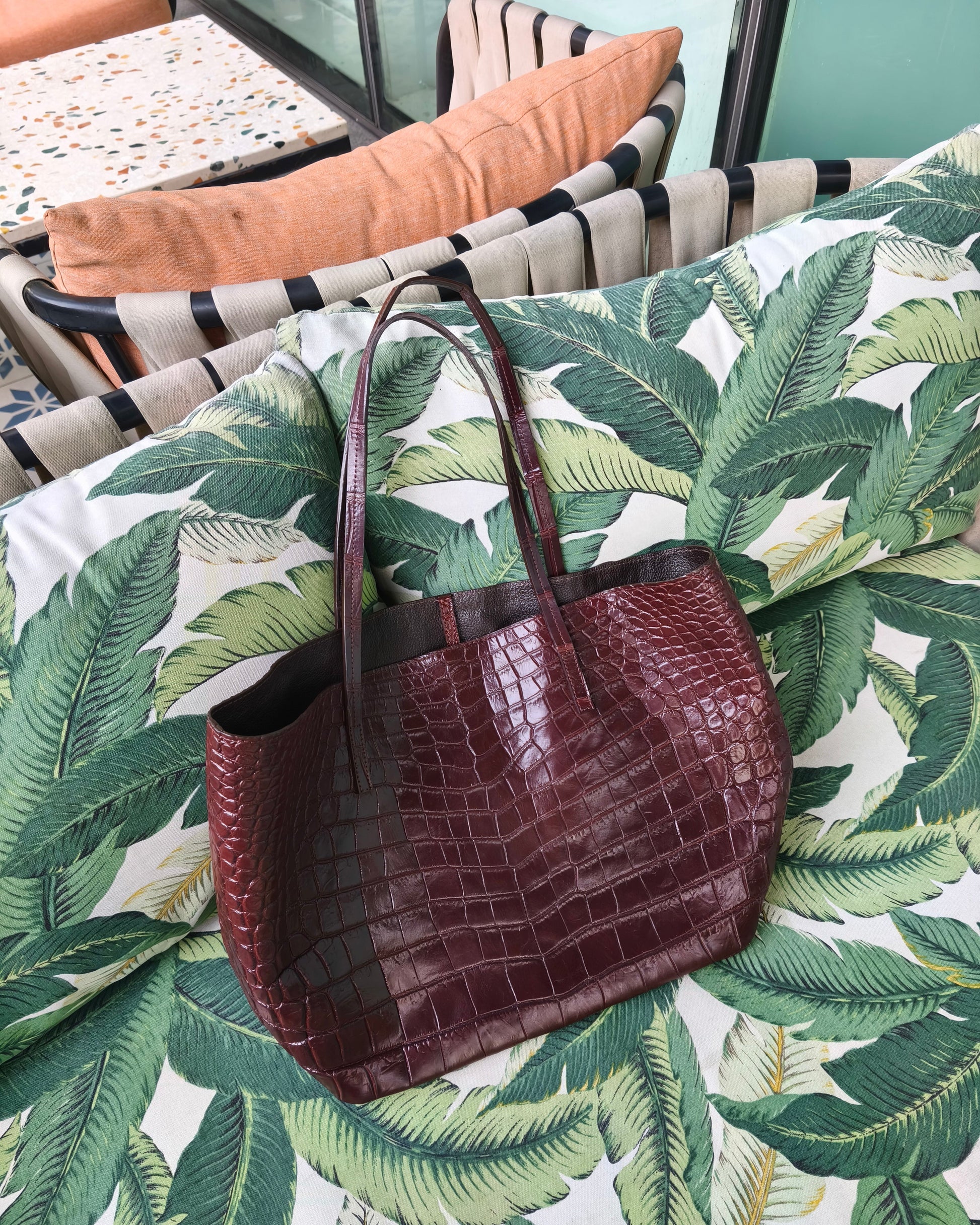 Brown textured handbag on a surface with a leaf pattern