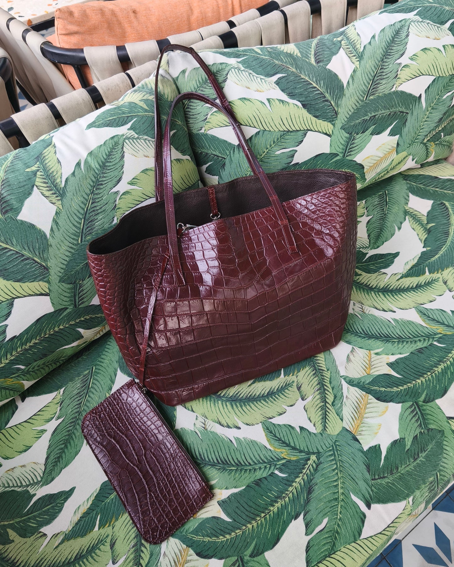 Brown crocodile-patterned handbag on a green leaf-patterned surface