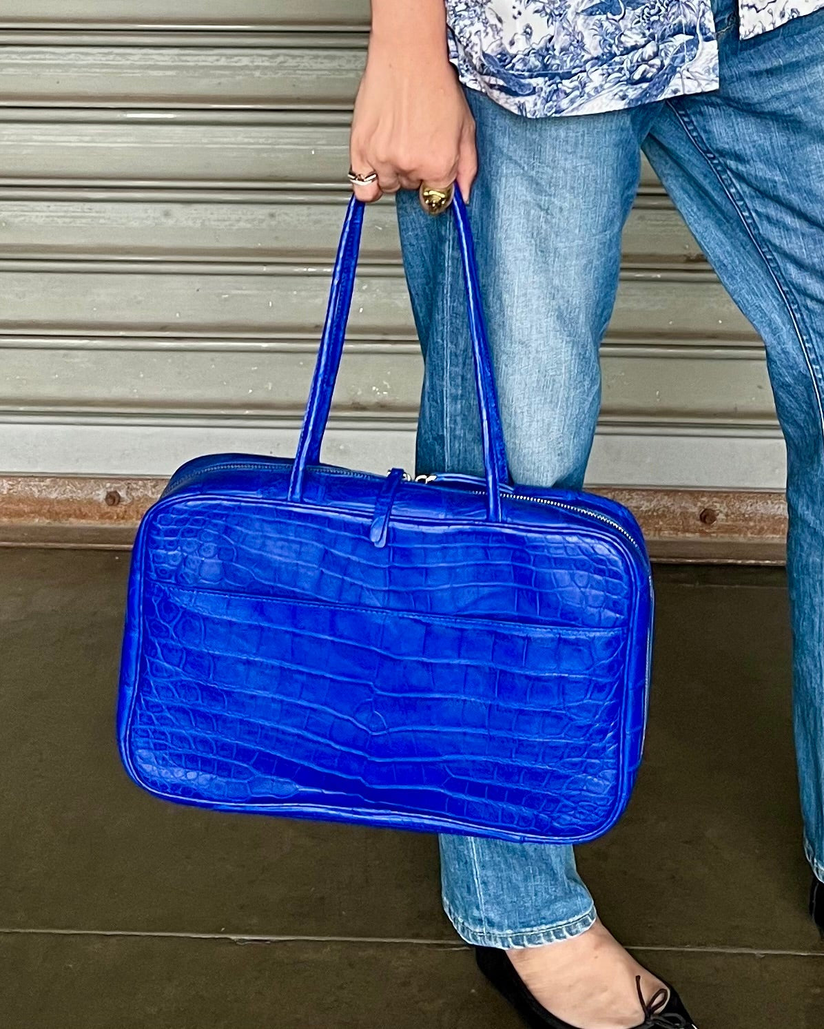 Person holding a blue textured bag with a neutral background