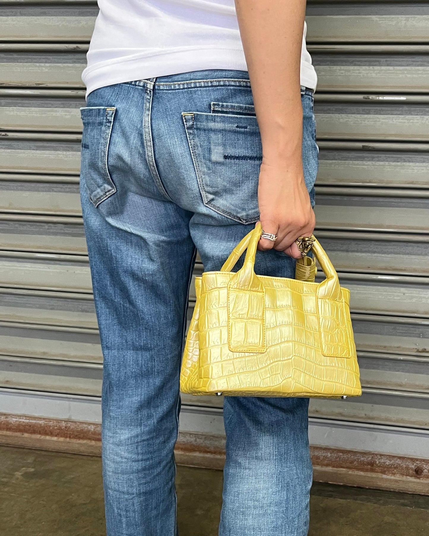 Person holding a yellow handbag with striped flooring and a brown floor.