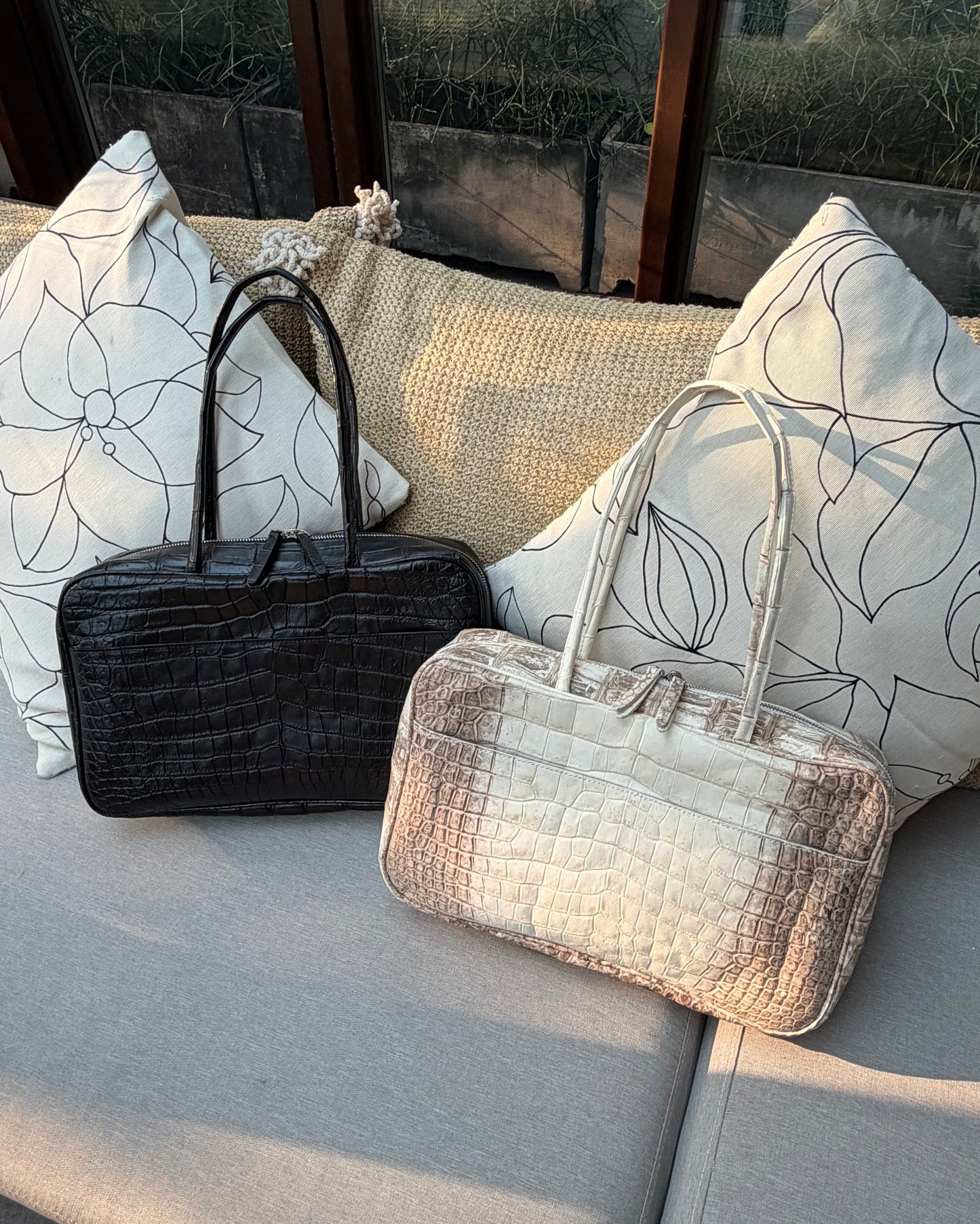Two handbags on a textured surface with a patterned background