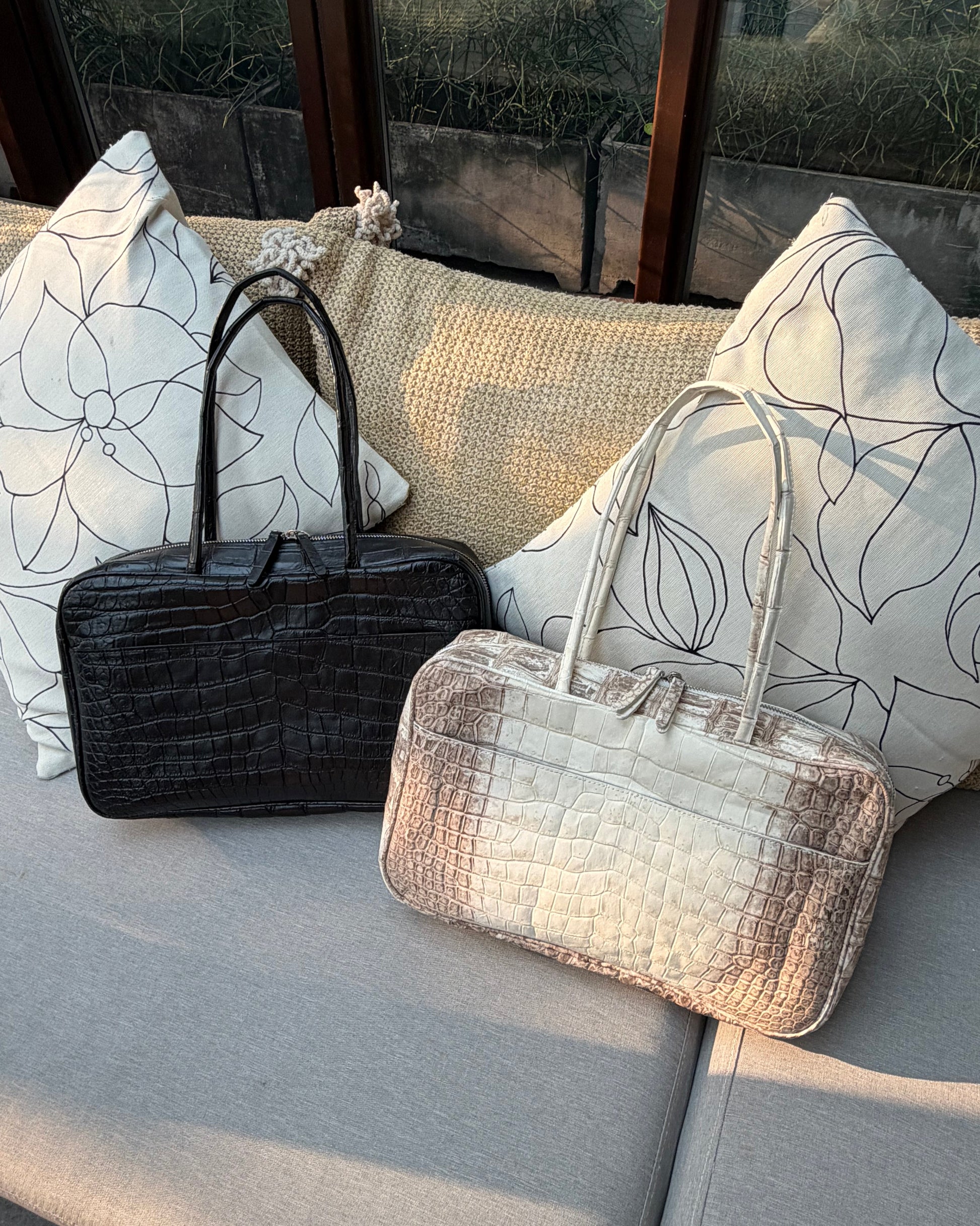 Two handbags on a textured surface with a patterned background