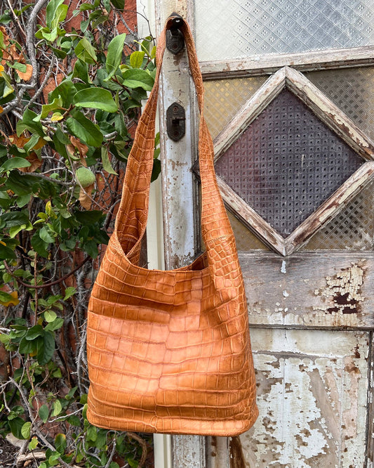 Brown leather handbag hanging on a rustic wooden door