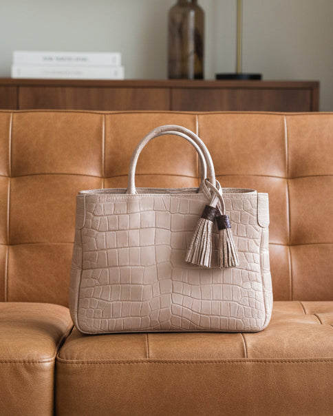 Pink textured handbag with a tassel on a striped surface